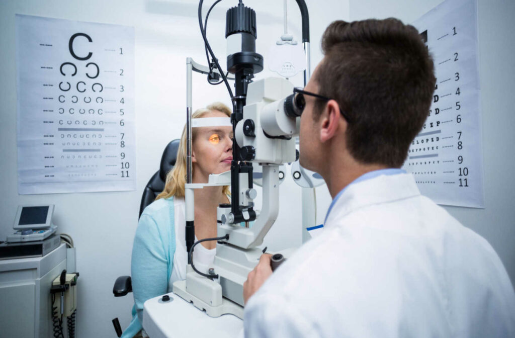 An optometrist evaluates a patient's eyes in an exam room.