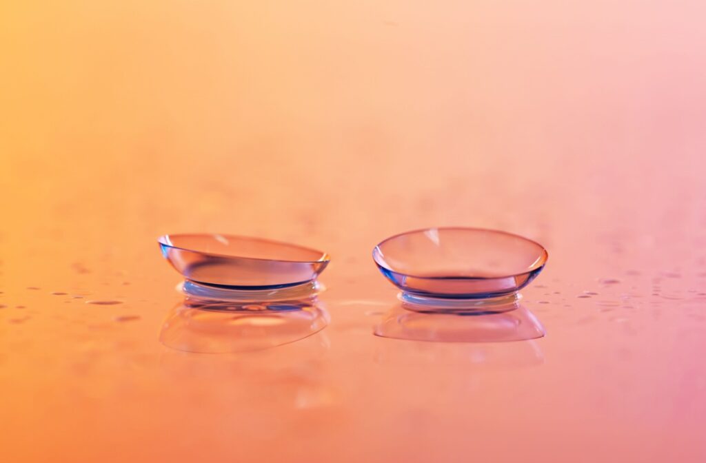 Close-up of contact lenses in solution against a pink and orange background.