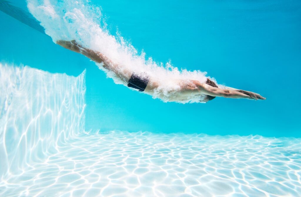 Side-view of a person underwater after diving into a chlorine swimming pool.