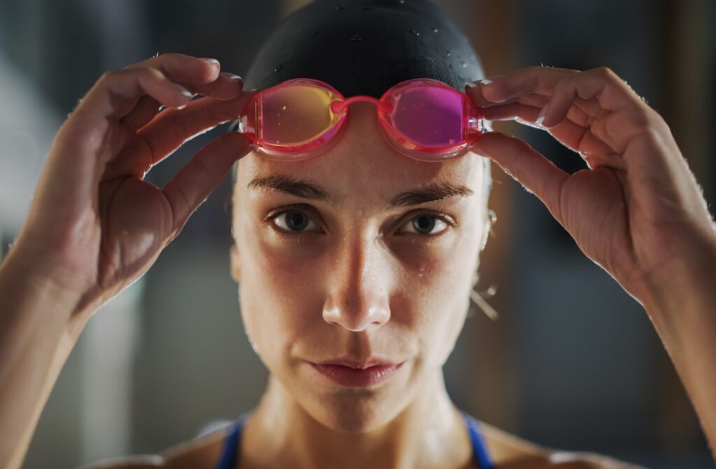 Close-up of a swimmer pulling pink goggles off and placing them on their forehead after a swim.