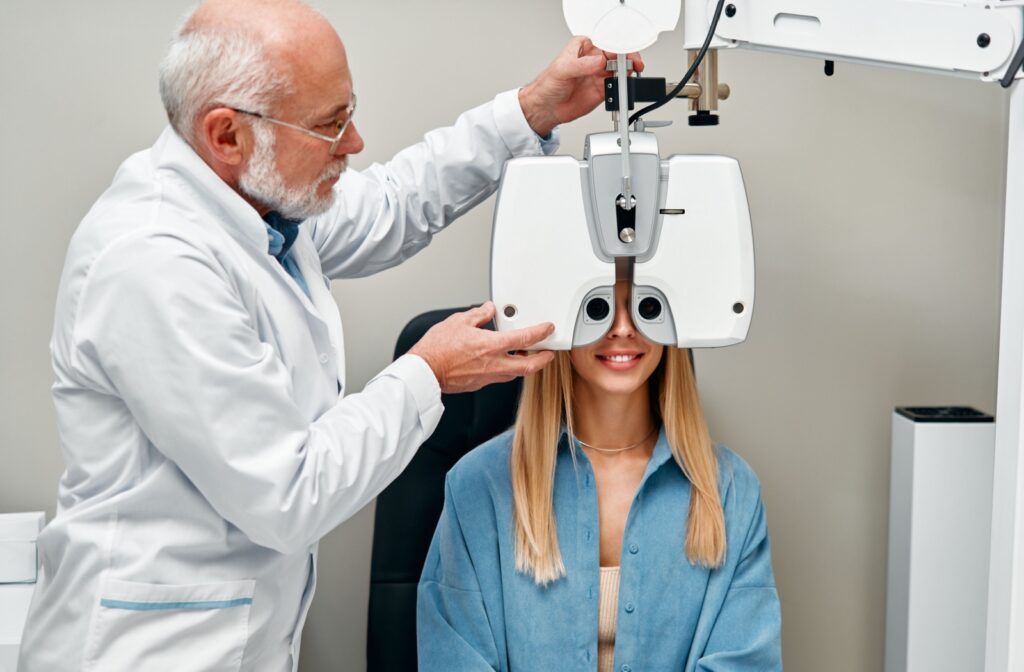 An optometrist using a phoropter during a patient's annual eye exam to determine their eyeglass prescription.