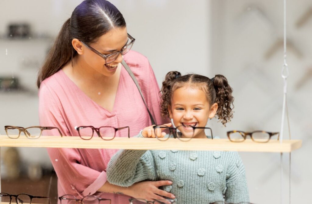A young girl and her mom smiling while looking at glasses options to correct myopia.
