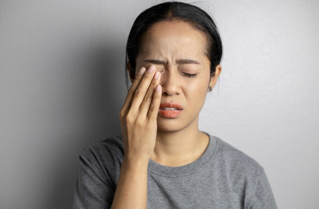 A person holding their eye due to their contact lens feeling scratchy.
